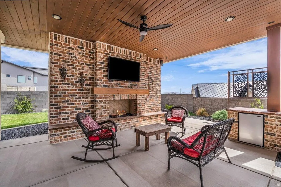 View of patio / terrace with ceiling fan and an outdoor living space with a fireplace