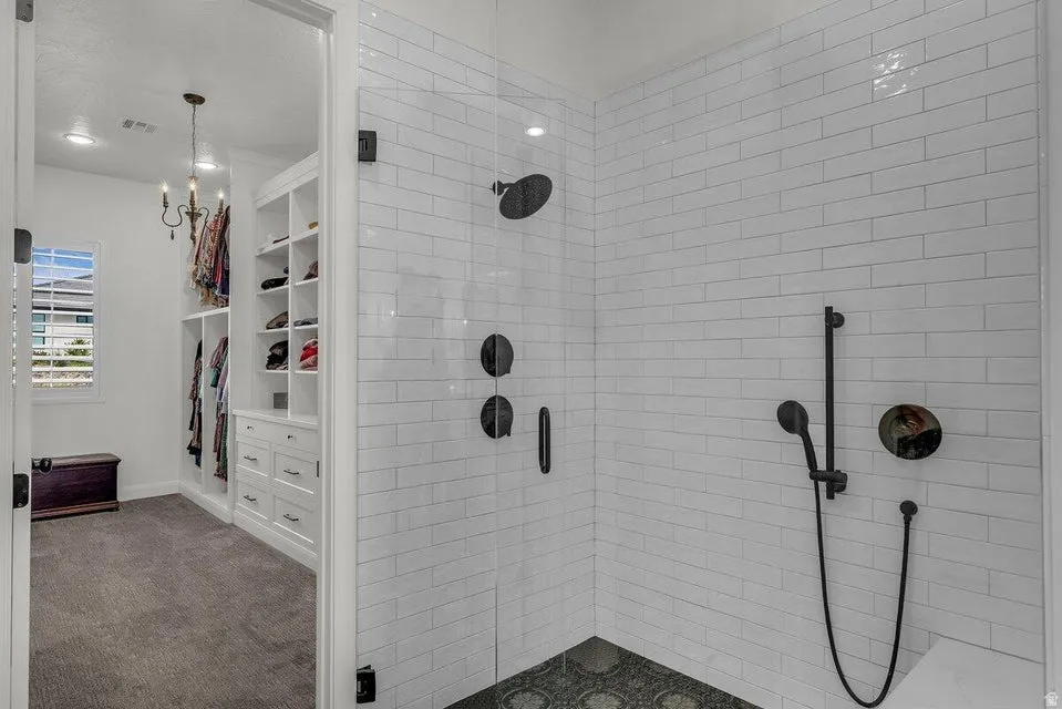 Bathroom featuring a walk in closet, a stall shower, and carpet flooring
