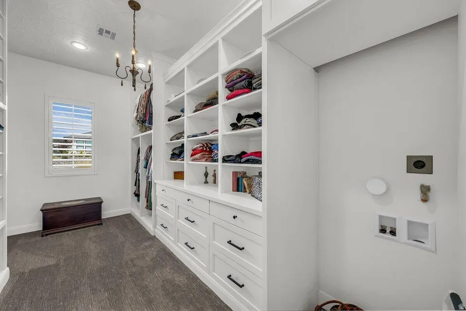 Walk in closet featuring dark colored carpet and suspended lighting
