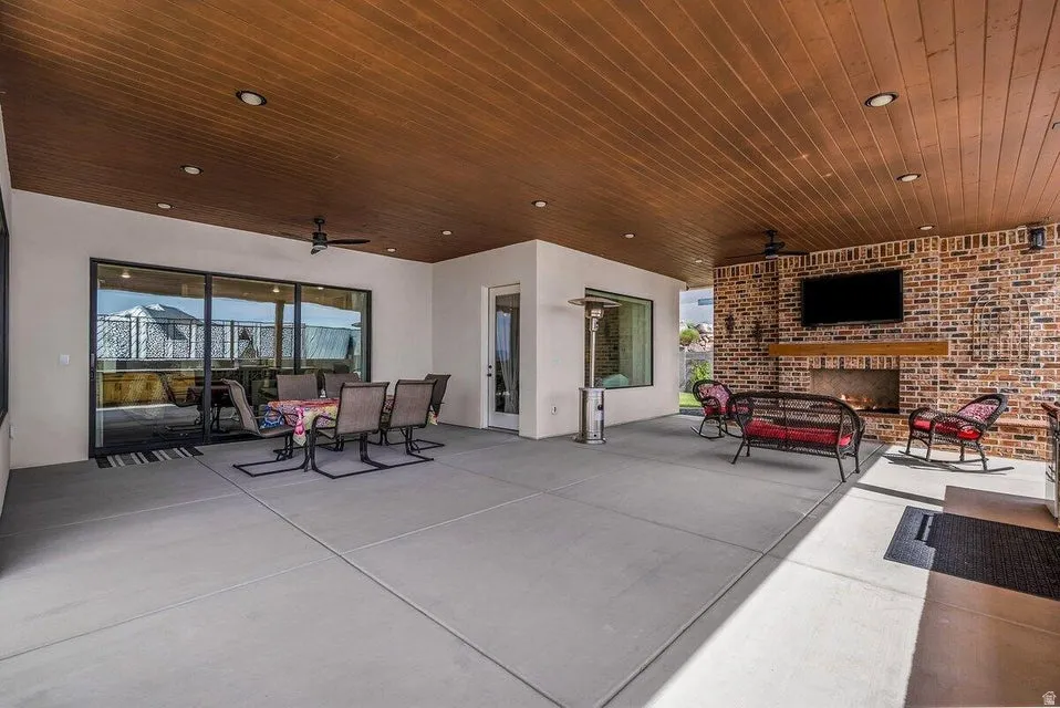 View of patio featuring an outdoor brick fireplace, ceiling fan, and outdoor lounge area