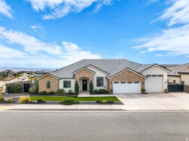 View of front of house with an attached garage, stucco siding, concrete driveway, and a tiled roof