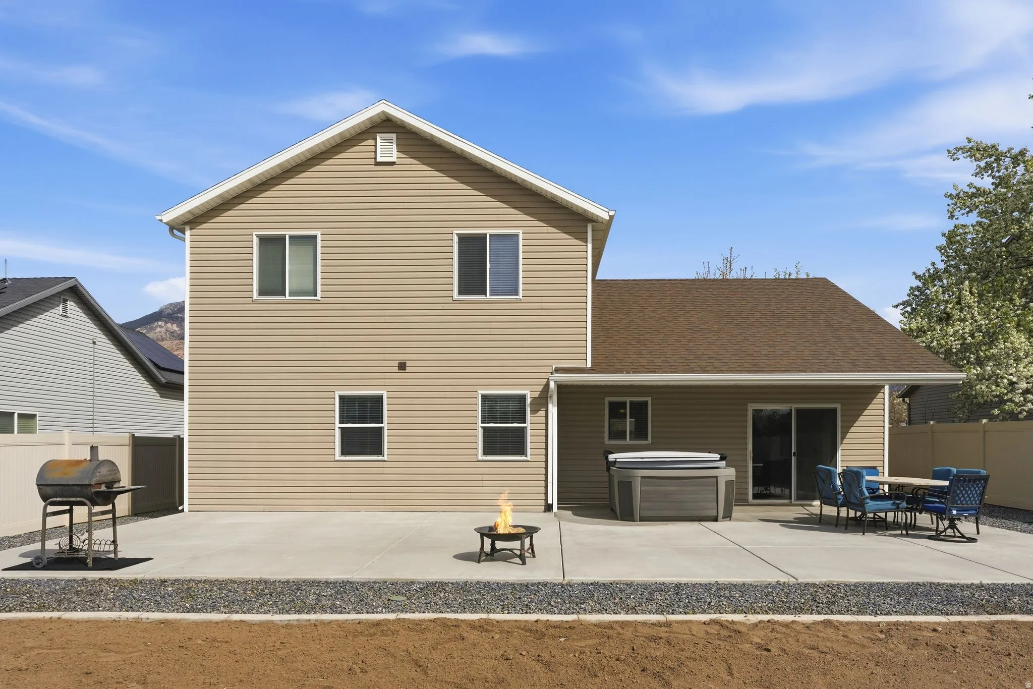 Rear view of house featuring a patio, outdoor dining space, a hot tub, an outdoor fire pit, and roof with shingles