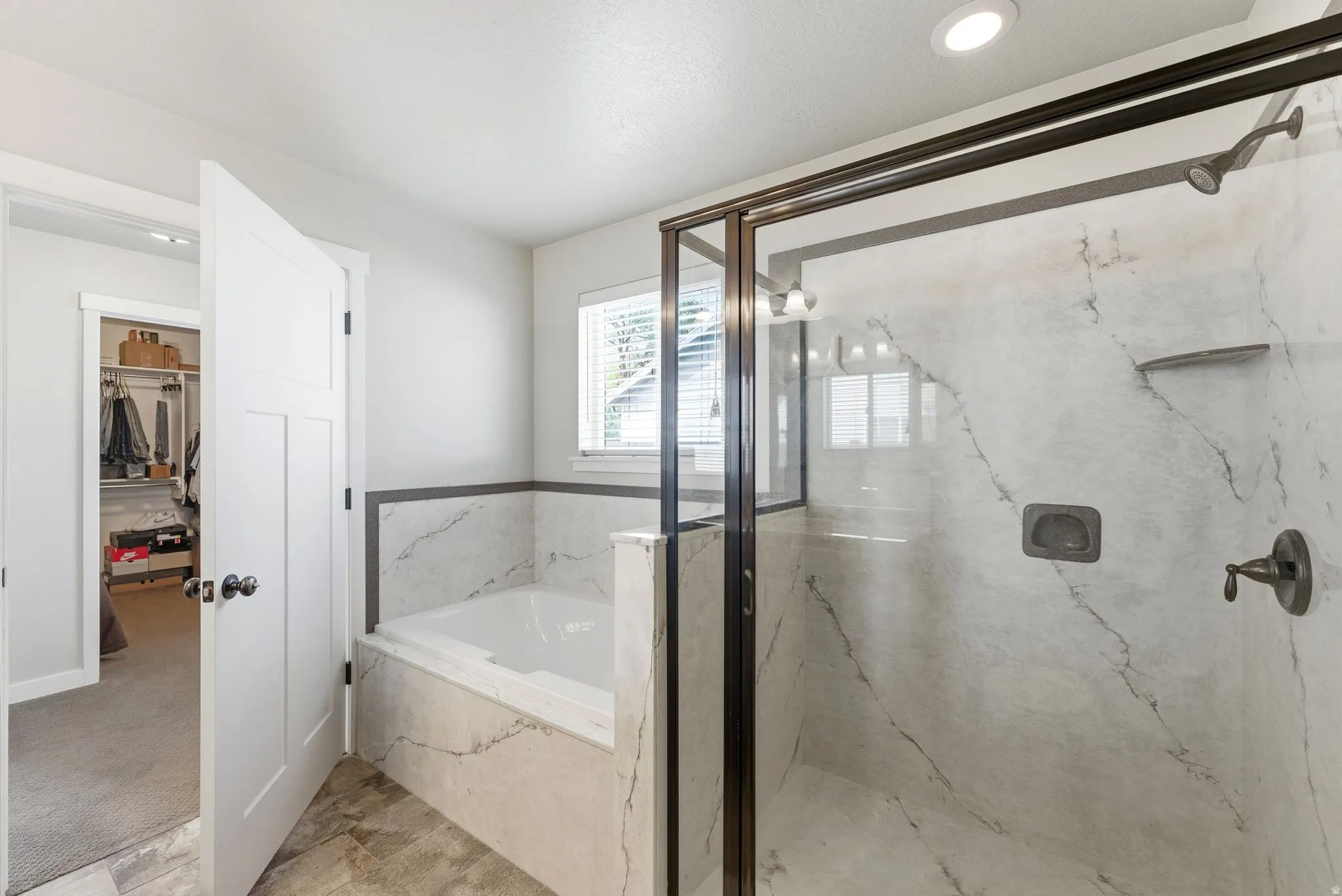 Full bathroom featuring a marble finish shower, a garden tub, a walk in closet, and recessed lighting