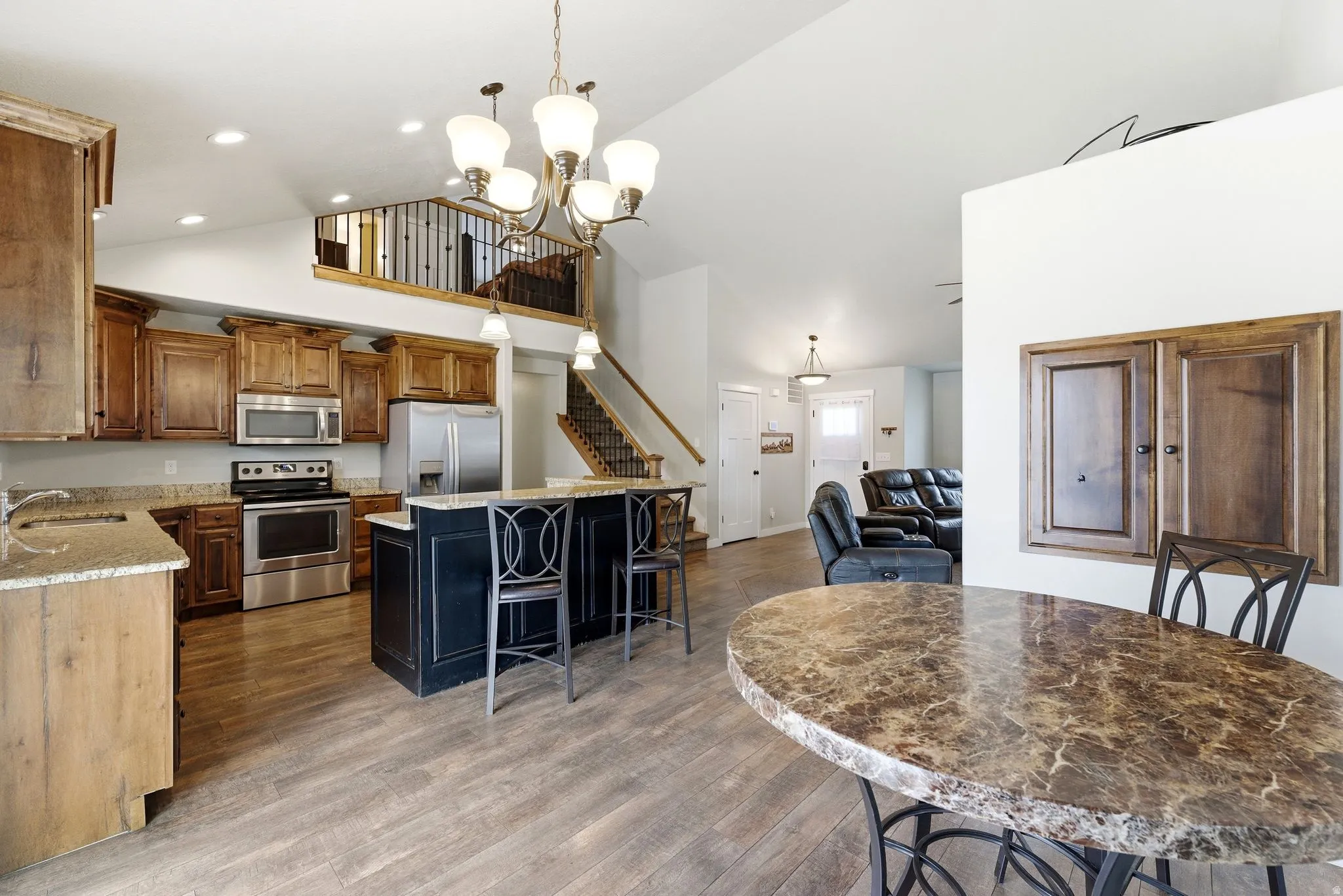Kitchen featuring light stone countertops, stainless steel appliances, a center island, a kitchen breakfast bar, and vaulted ceiling
