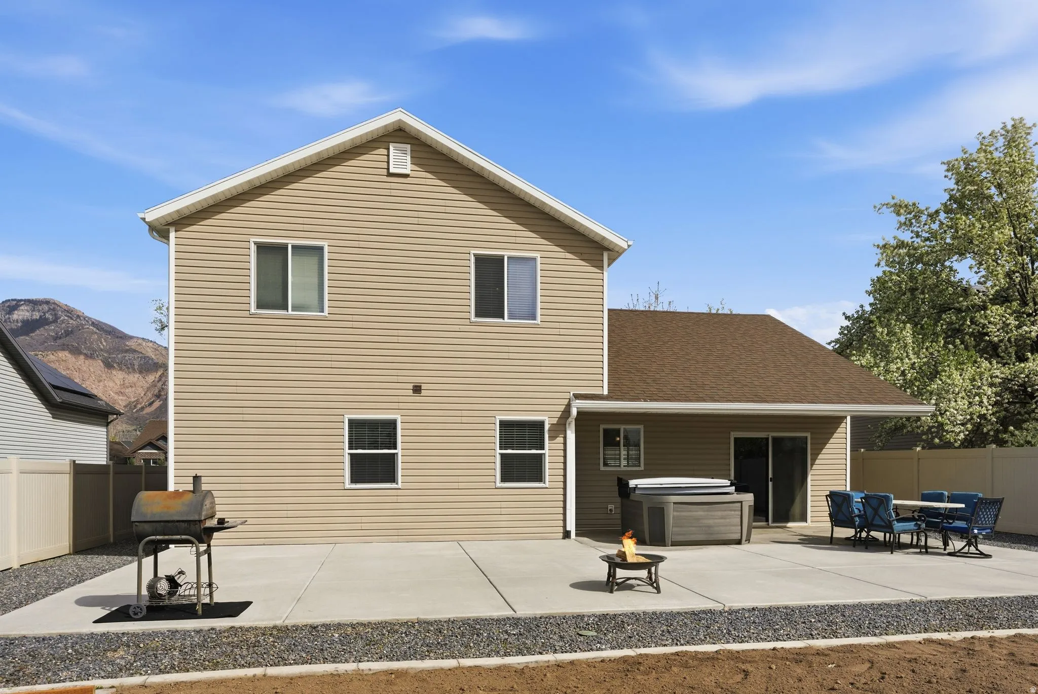 Back of property with a patio area, a fenced backyard, an outdoor fire pit, a shingled roof, and a hot tub