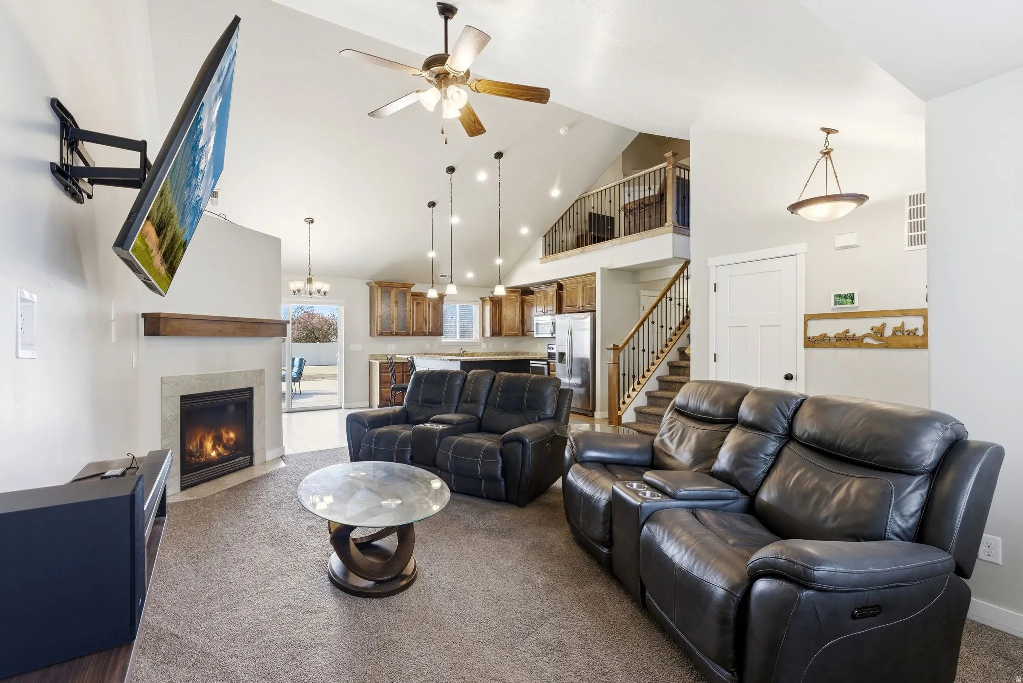 Living room featuring a ceiling fan, a tile fireplace, dark colored carpet, and lofted ceiling