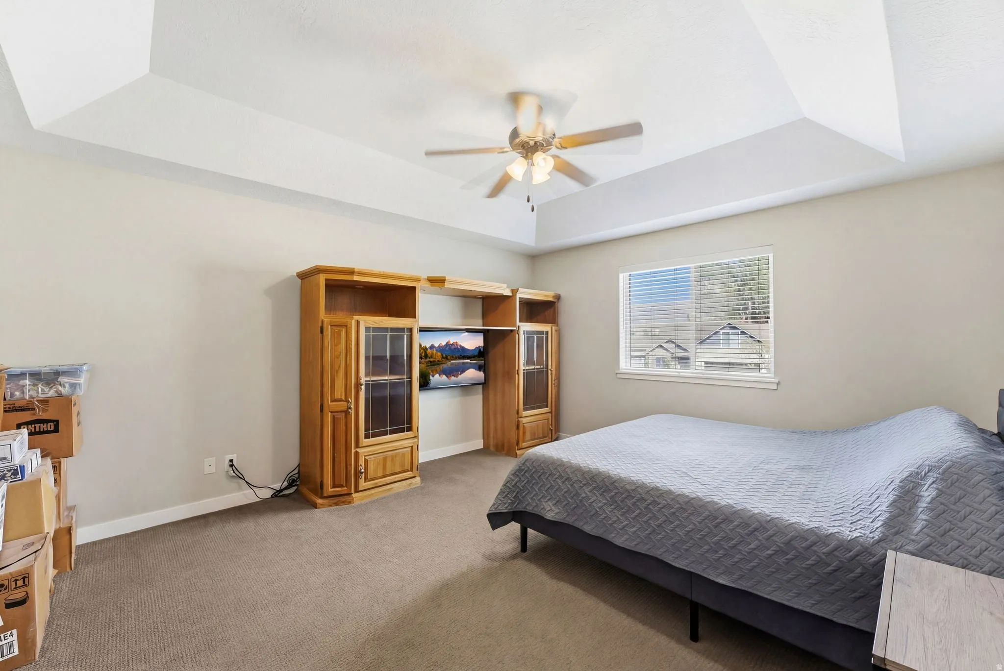 Bedroom with a tray ceiling, carpet floors, and ceiling fan