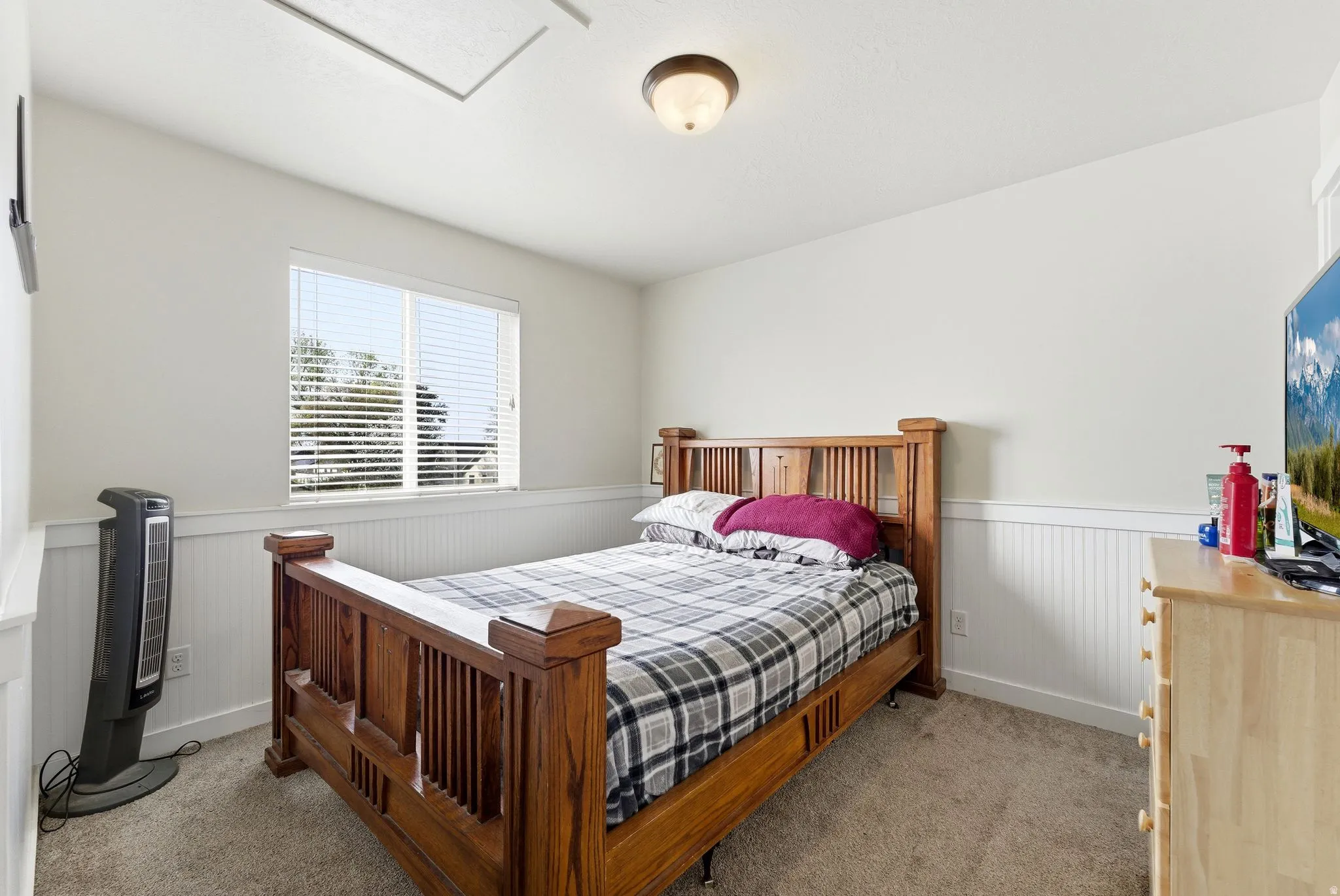 Bedroom with wainscoting and light carpet