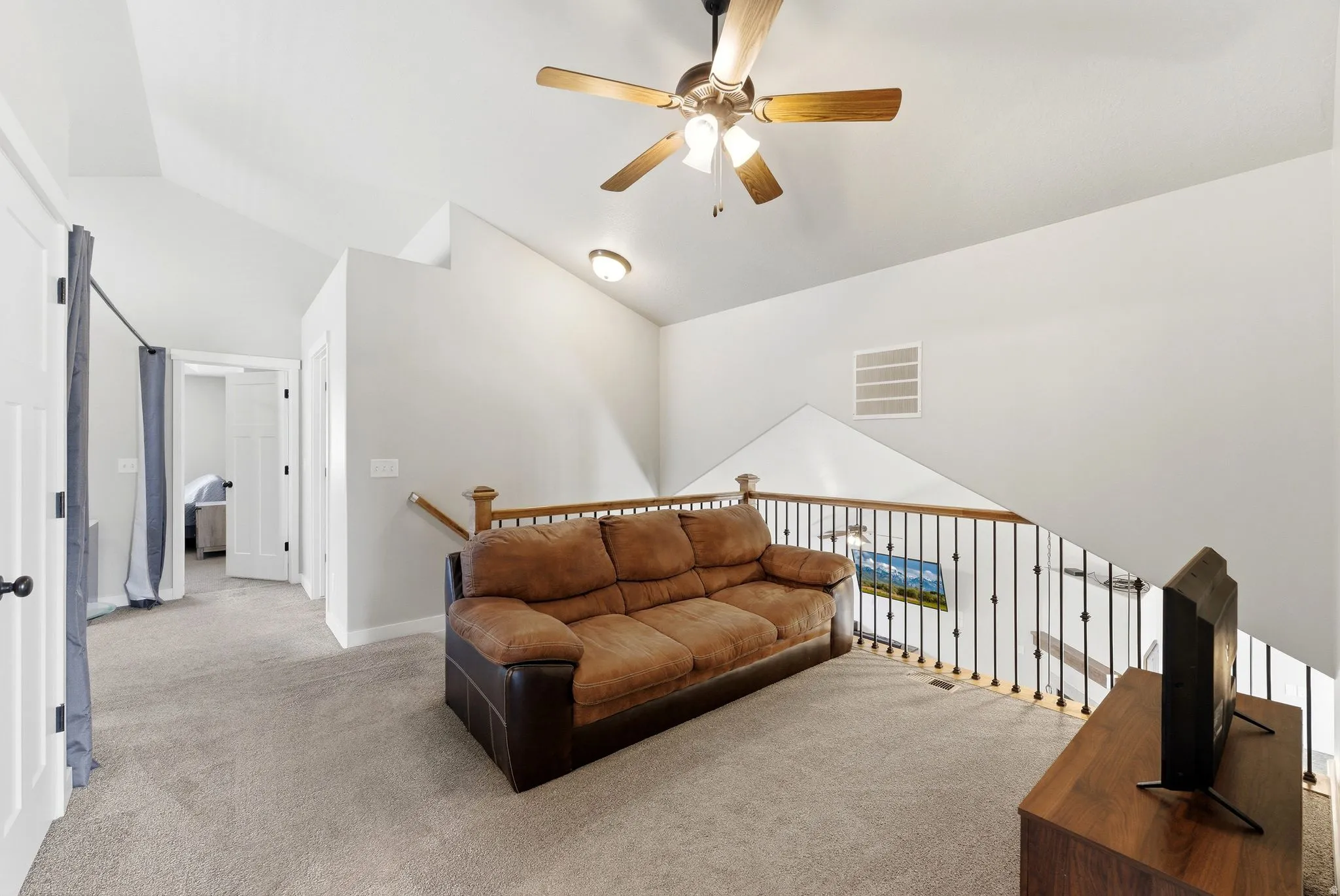 Carpeted living room with lofted ceiling and a ceiling fan