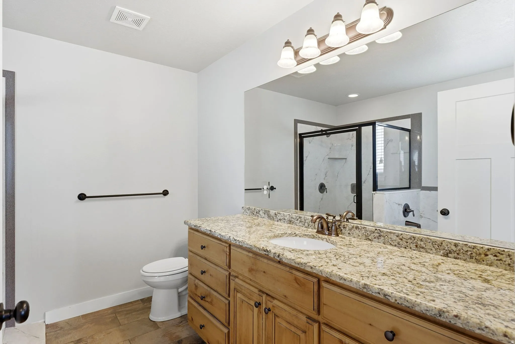 Bathroom featuring a shower stall, vanity, and light wood finished floors
