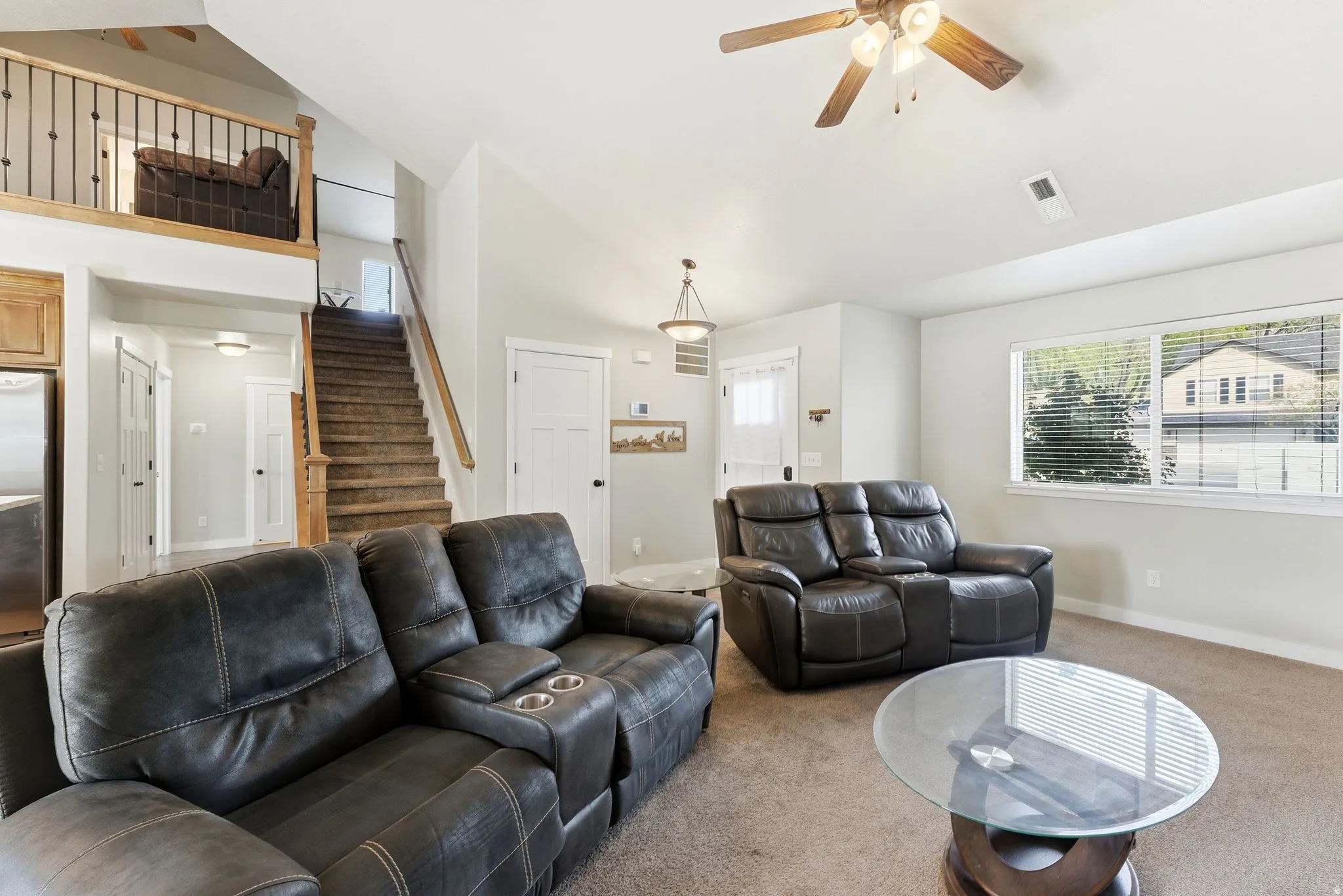 Carpeted living room featuring ceiling fan and vaulted ceiling