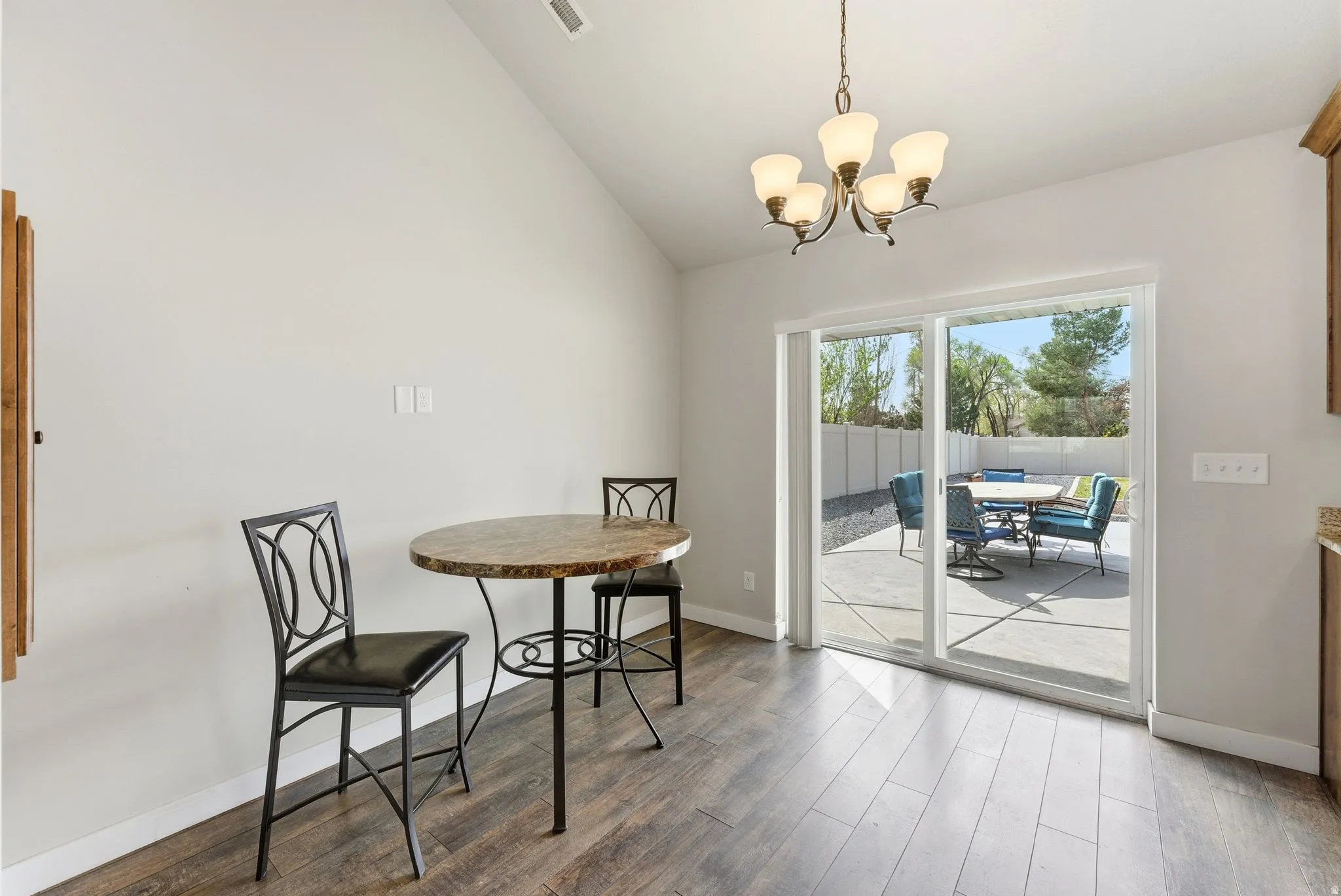 Dining space with lofted ceiling, wood finished floors, and a chandelier