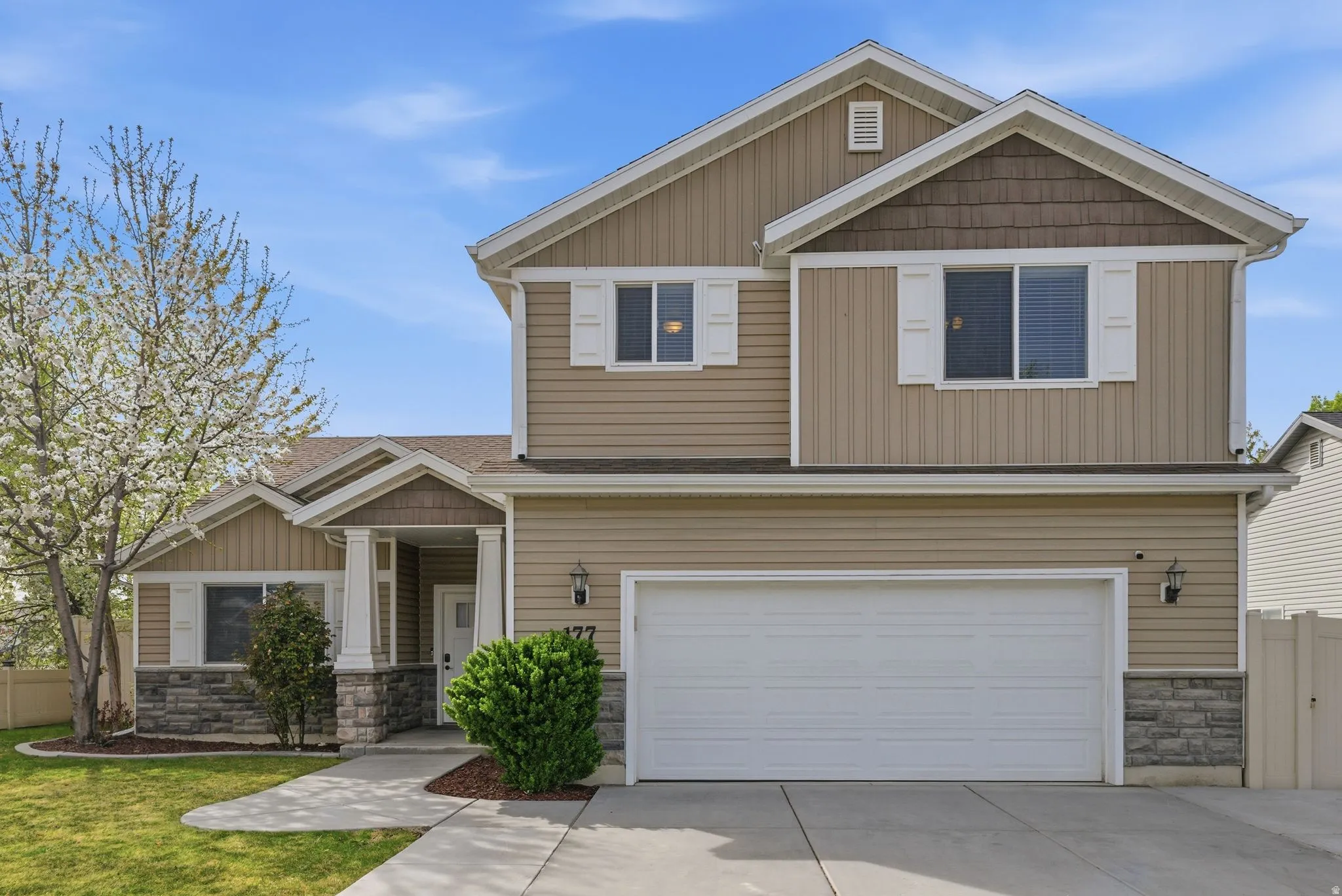 Craftsman house with stone siding, a garage, and driveway