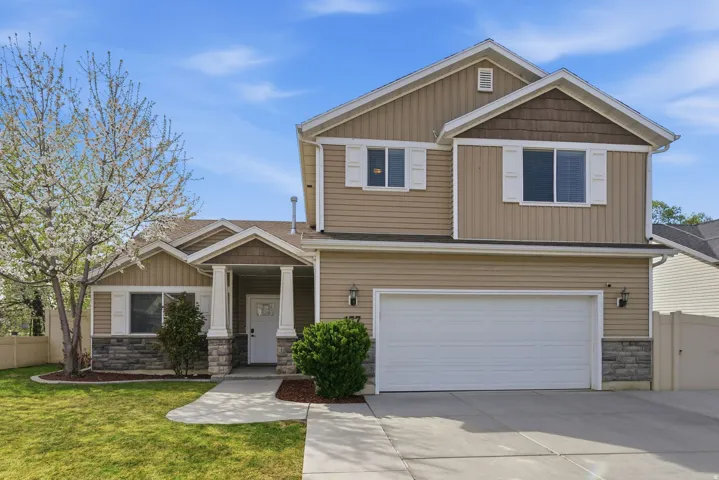 Craftsman-style home featuring stone siding, a garage, driveway, and board and batten siding