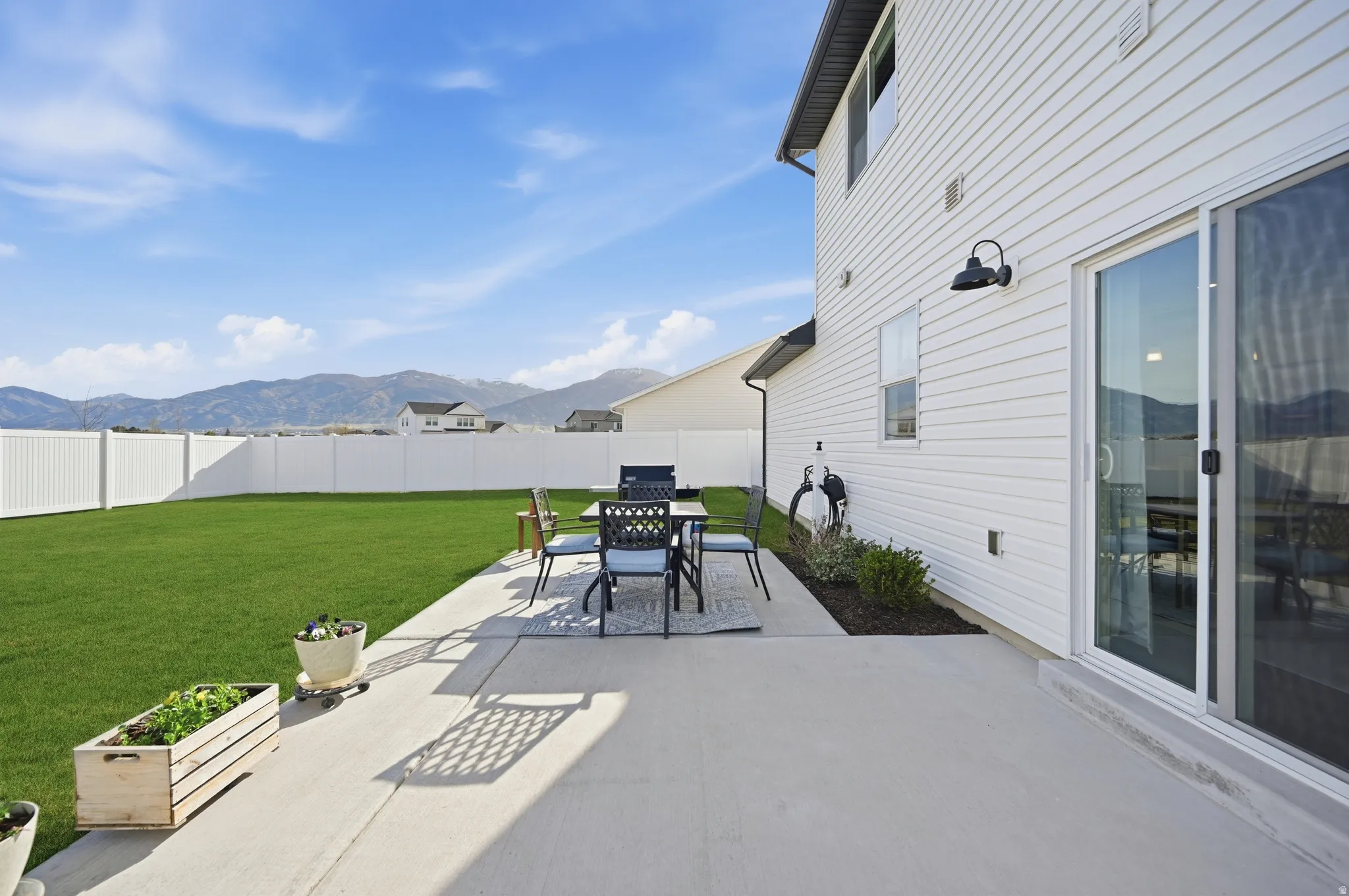 Fenced backyard featuring a mountain view, a patio, and outdoor dining area