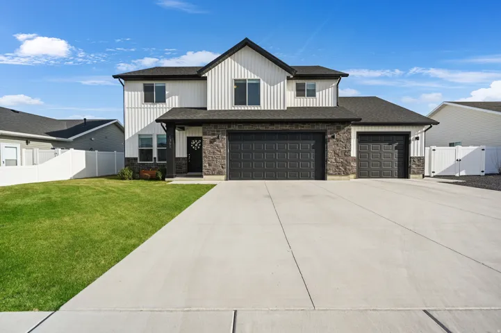 Modern inspired farmhouse with a gate, driveway, stone siding, and an attached garage