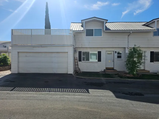 View of front of property with a metal roof, asphalt driveway, and an attached garage