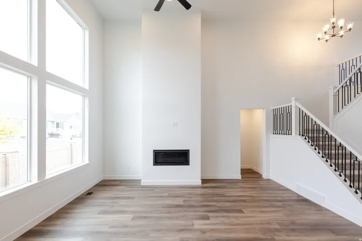 Spacious living area featuring large picture windows, a modern linear fireplace, and wood-finish flooring
