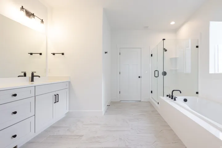 Bathroom featuring a spacious double vanity with white cabinetry, matte black hardware, and a light-toned countertop