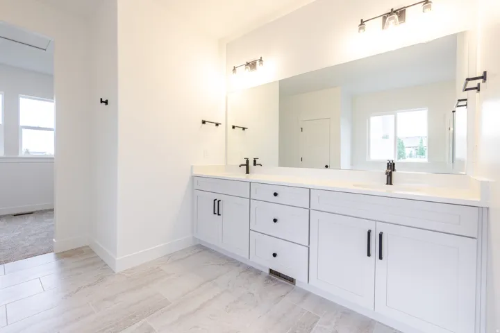 Double vanity featuring white cabinetry, black hardware, and an expansive mirror