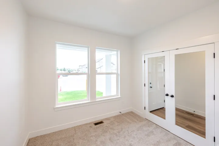 Room featuring twin windows providing natural light, white trim throughout, and neutral carpeting