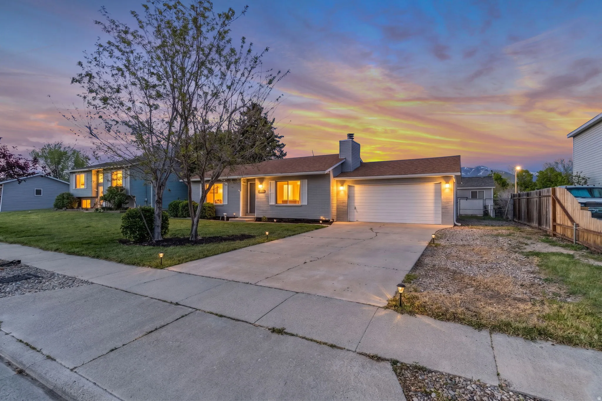 Single story home with an attached garage, a chimney, and concrete driveway