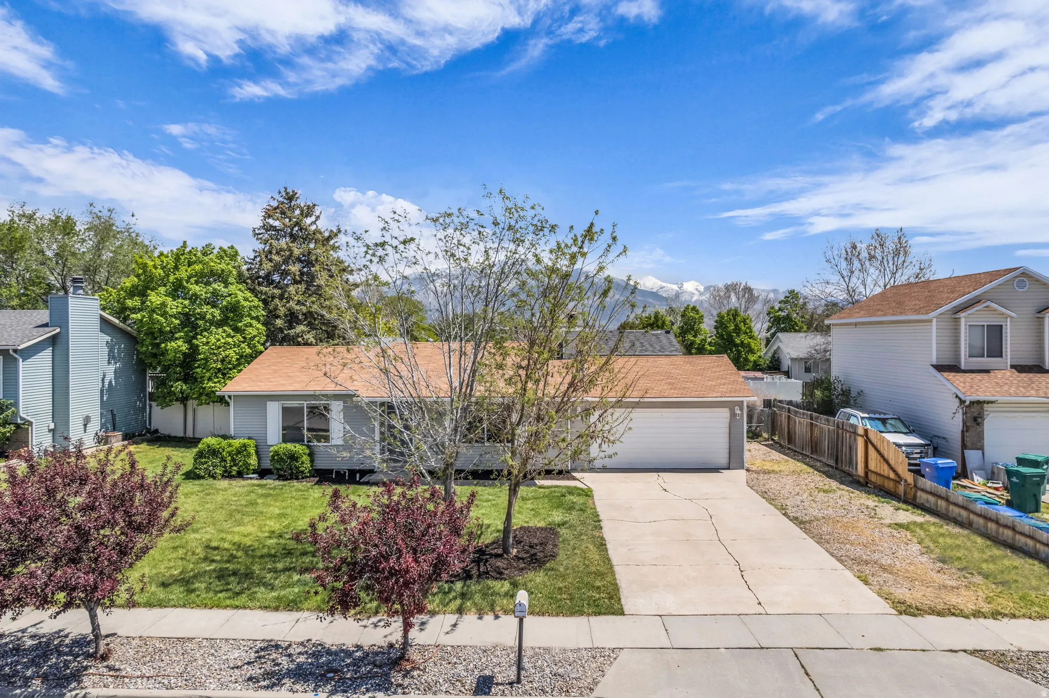View of front of home featuring driveway, a garage, a mountain view, and roof with shingles