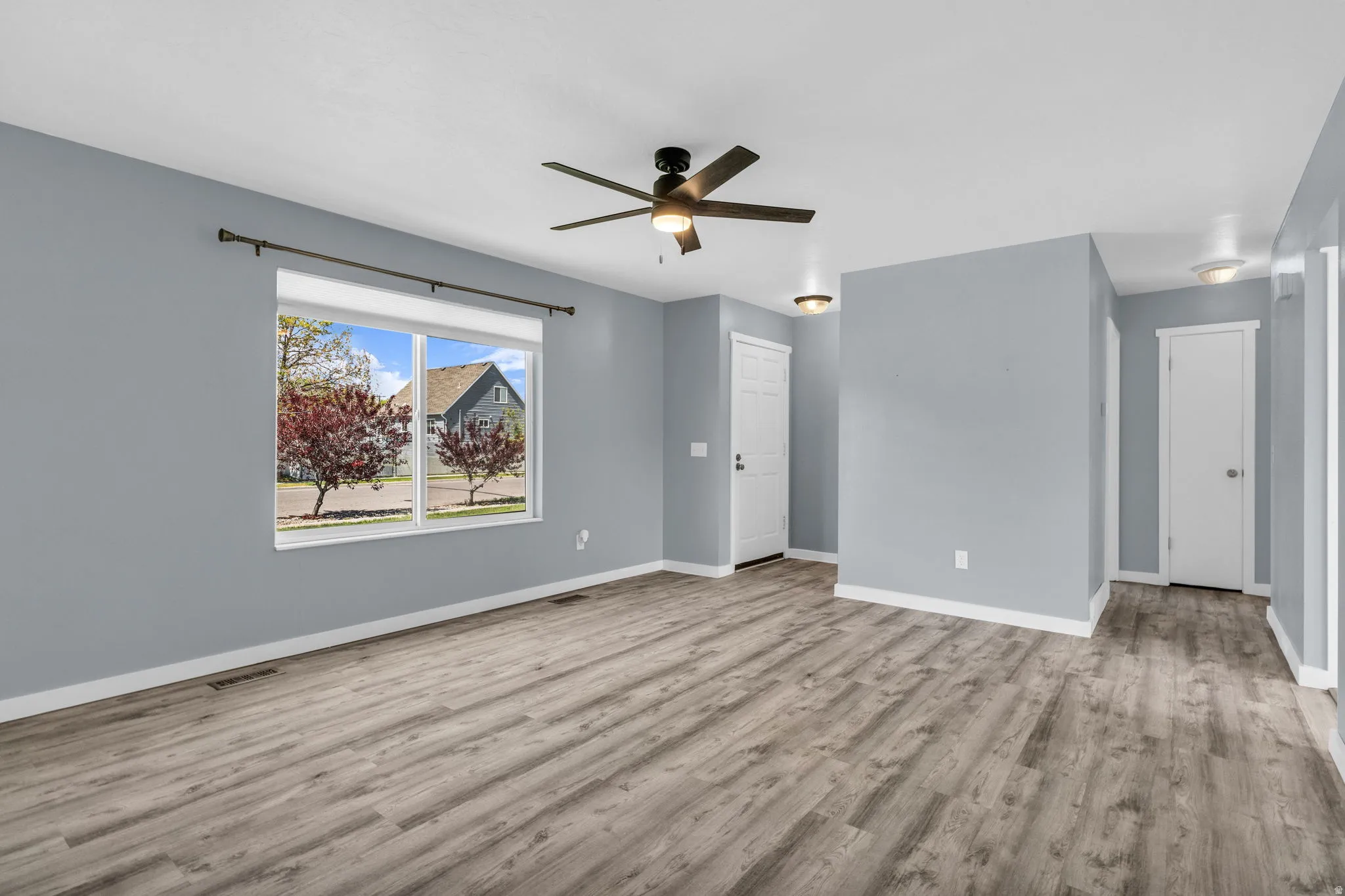 Unfurnished living room with ceiling fan and light wood-style flooring