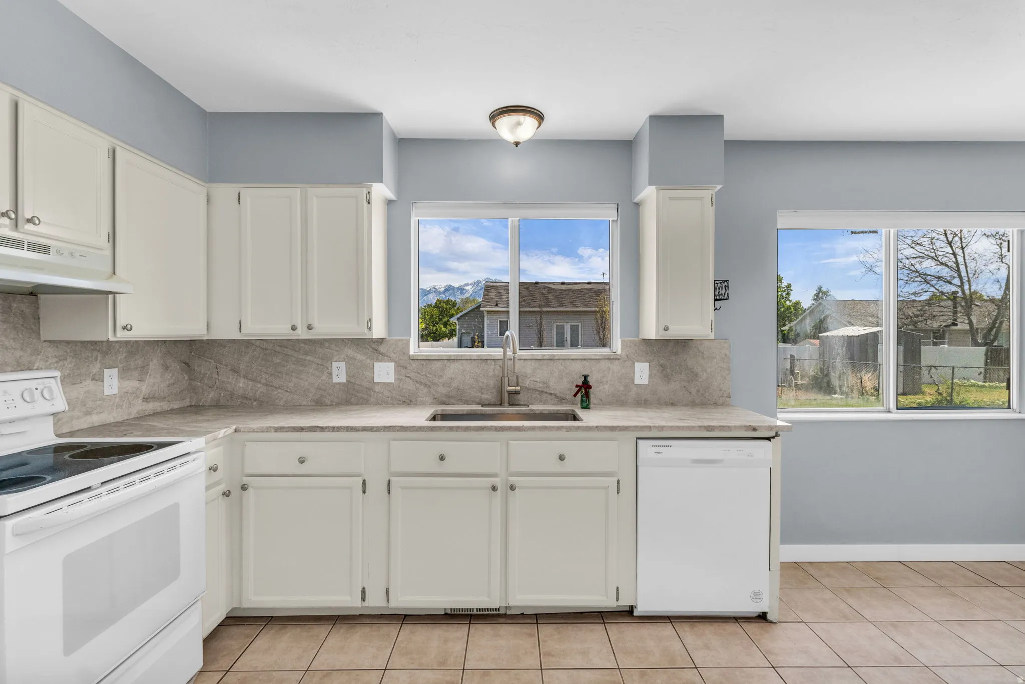 Kitchen featuring white appliances, white cabinetry, and light tile patterned floors