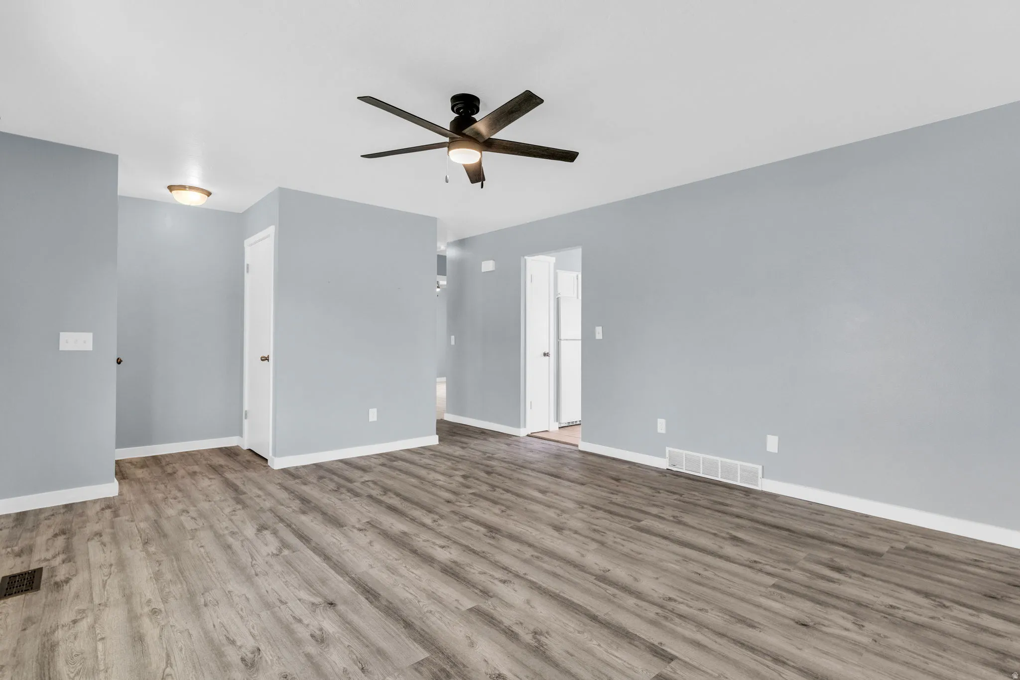 Empty room with a ceiling fan and light wood-style flooring