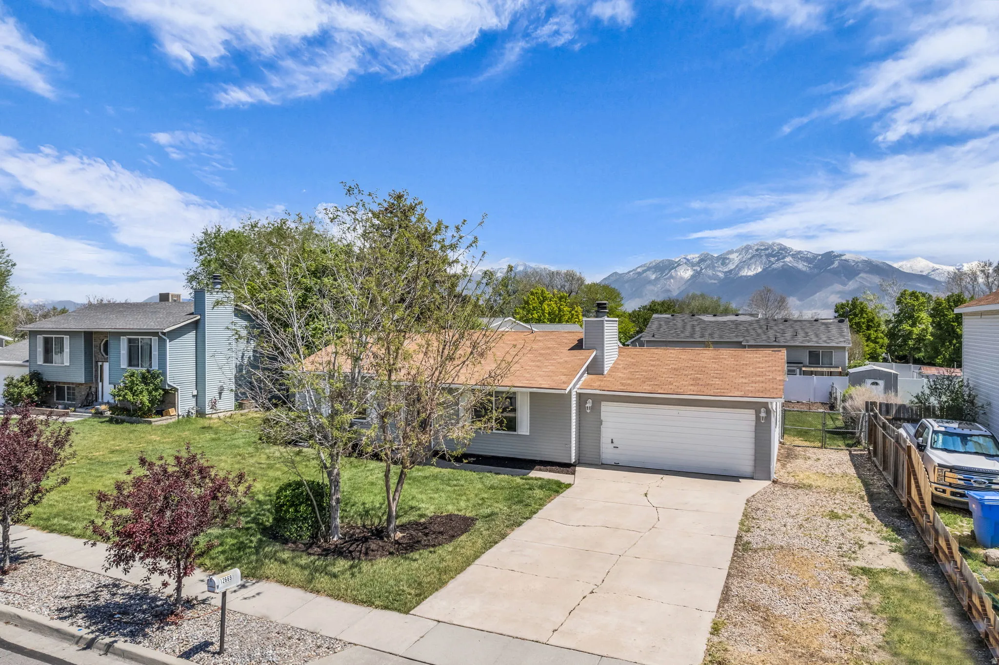 Ranch-style house with driveway, a chimney, a mountain view, an attached garage, and covered porch
