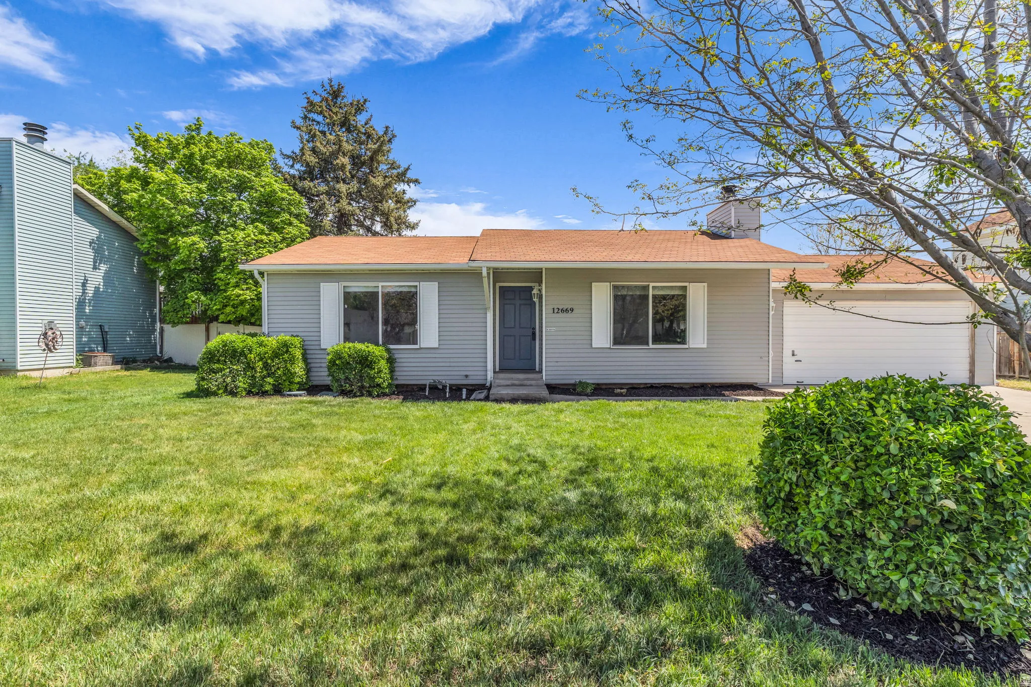 Ranch-style home with a front lawn, a chimney, and a shingled roof