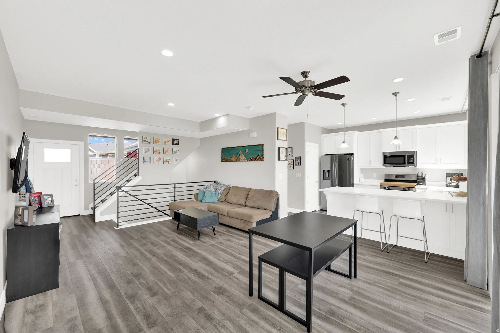 Living room featuring light wood-style flooring, ceiling fan, and recessed lighting