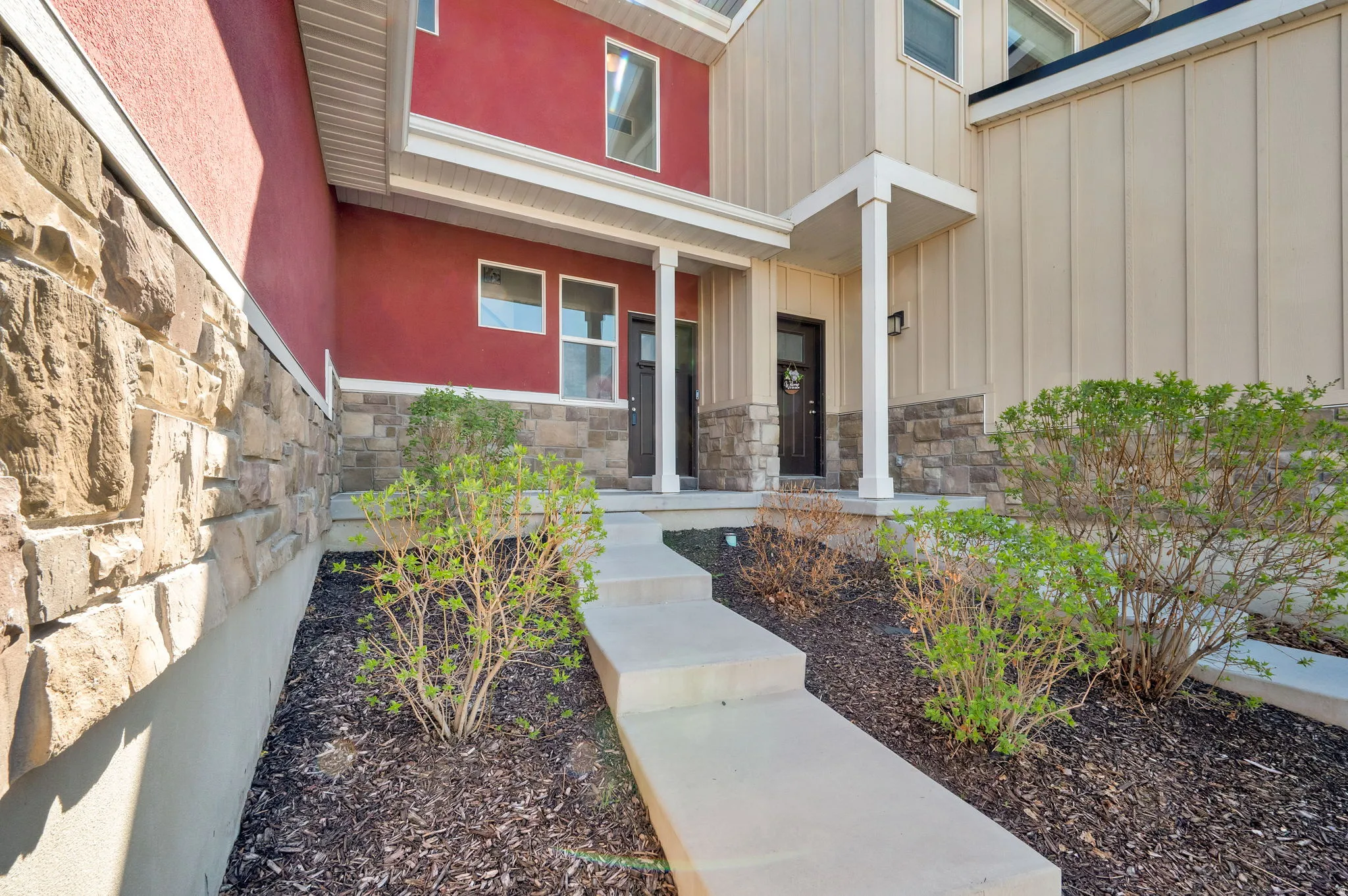 Entrance to property with stone siding, covered porch, and board and batten siding