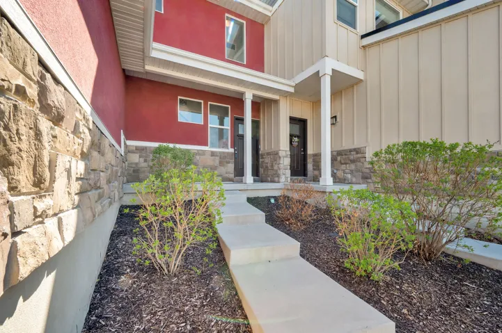Entrance to property with stone siding, covered porch, and board and batten siding