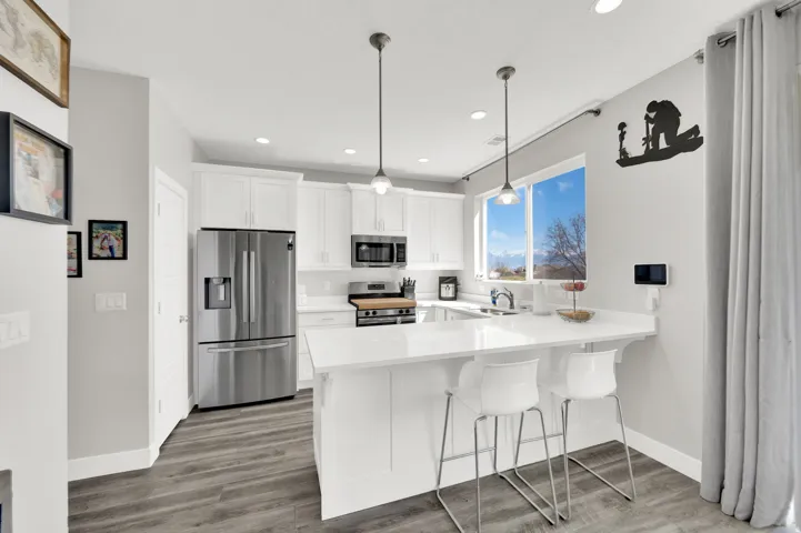 Kitchen with stainless steel appliances, white cabinets, a peninsula, a kitchen breakfast bar, and dark wood finished floors