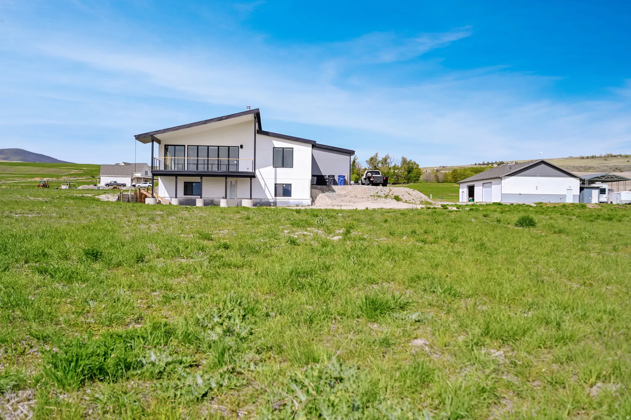 Back of house featuring a balcony, a mountain view, stucco siding, and a view of rural / pastoral area