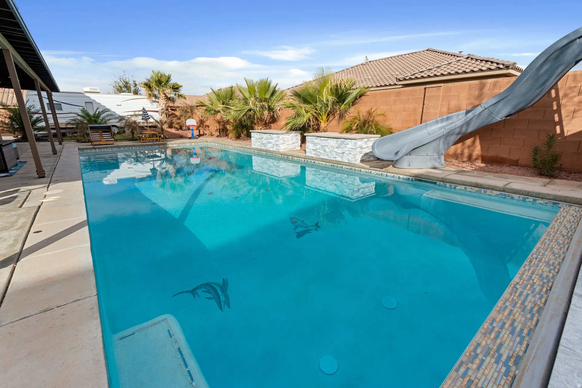 View of pool with a water slide, a fenced backyard, and patio surround