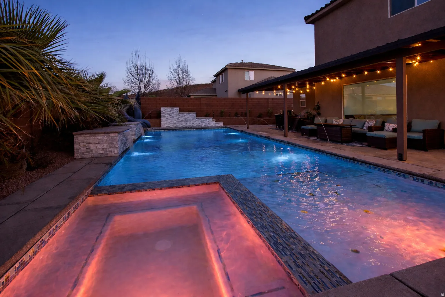 Pool at dusk with a fenced backyard, a patio area, a pool with connected hot tub, and an outdoor living space