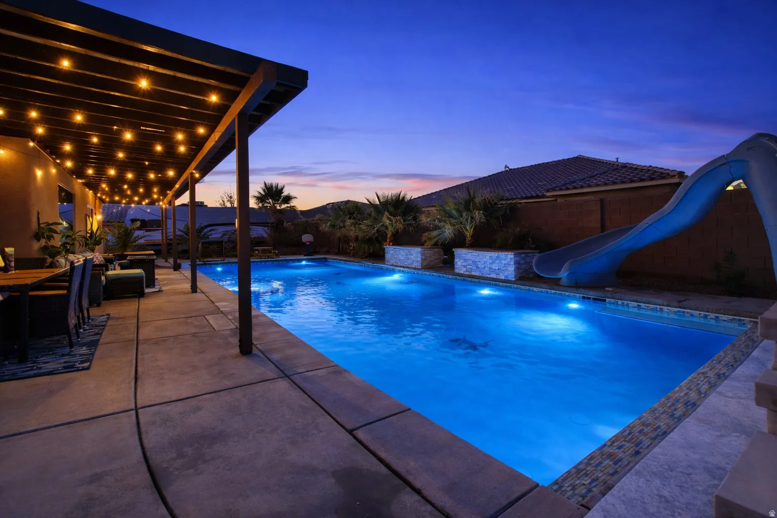 Swimming pool featuring a water slide, a patio area, and a fenced backyard