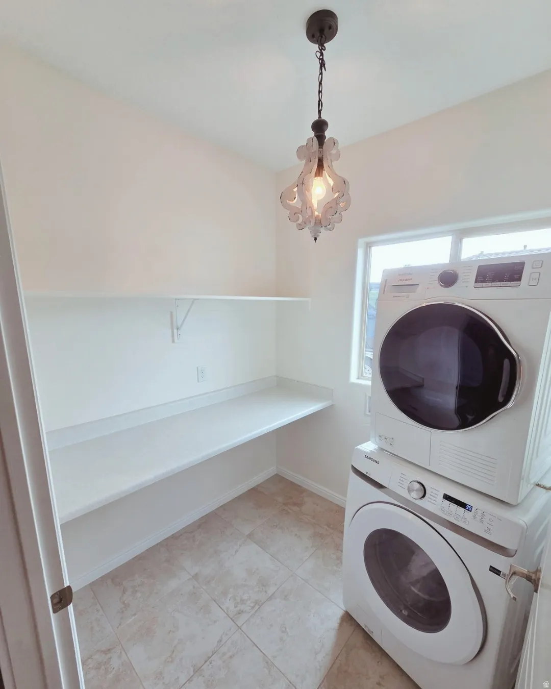 Laundry room featuring stacked washing machine and dryer and light tile patterned flooring