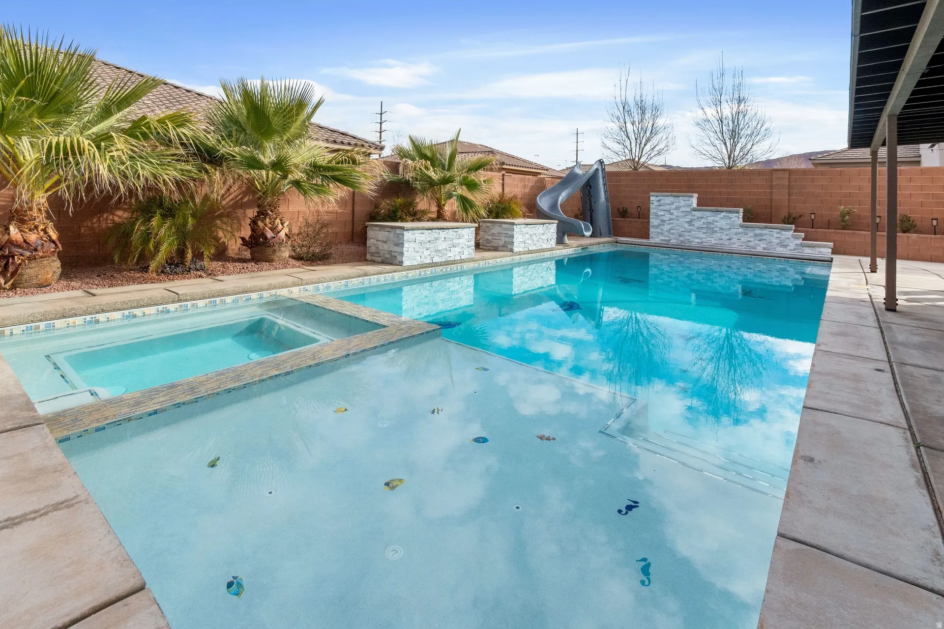 Combined pool / hot tub featuring a patio area, a water slide, and a fenced backyard