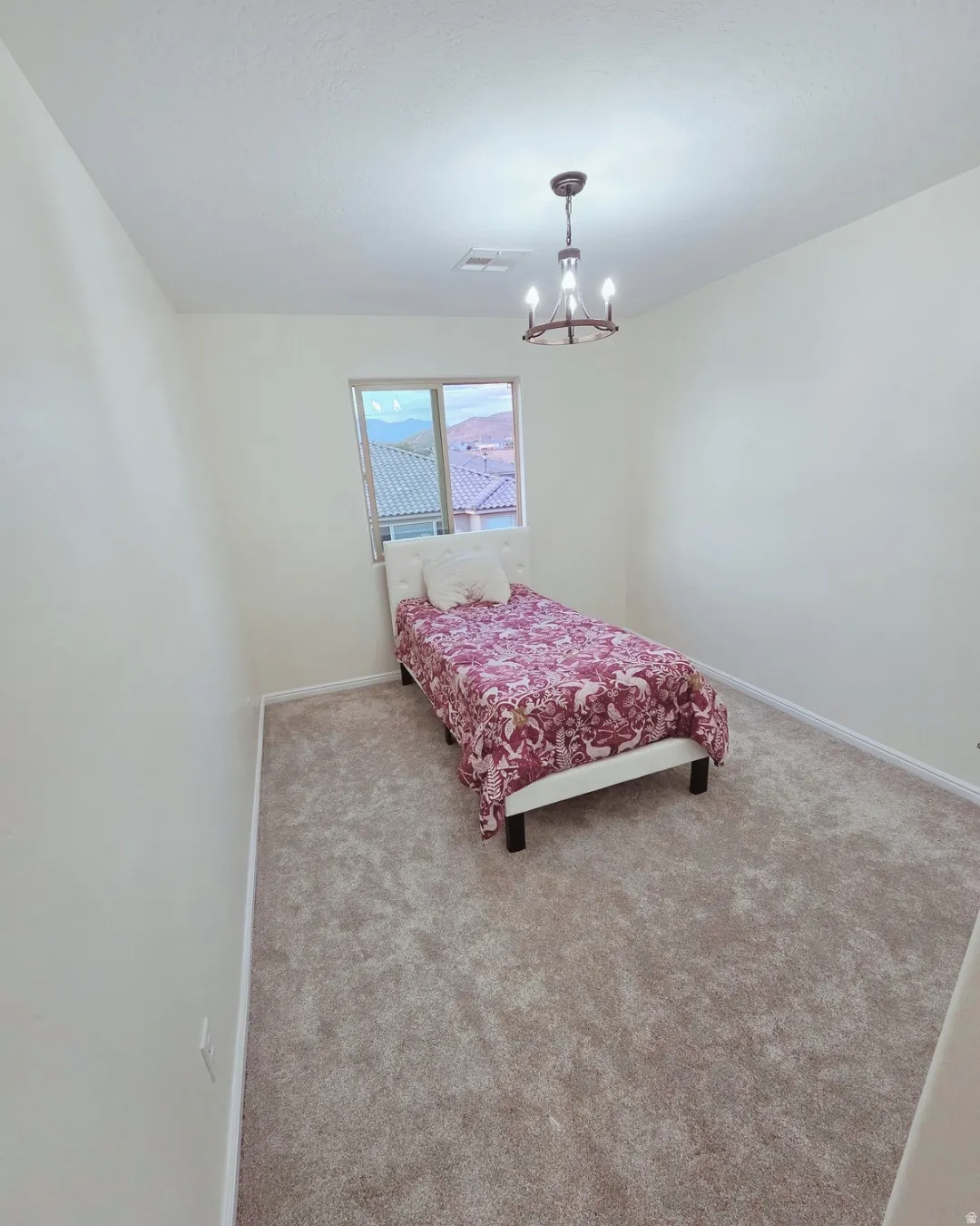 Bedroom with light carpet and hanging lights