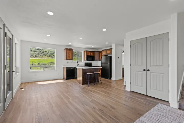 Kitchen featuring light countertops, a breakfast bar, recessed lighting, a kitchen island, and black appliances