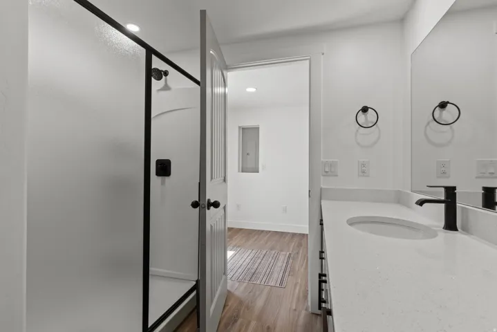 Bathroom with a shower stall, vanity, light wood-style floors, recessed lighting, and electric panel