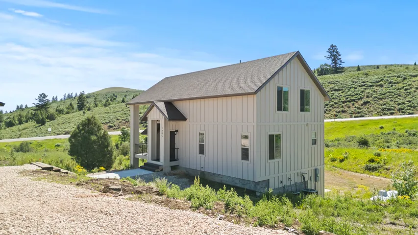 View of home's exterior with board and batten siding, roof with shingles, and a view of rural / pastoral area