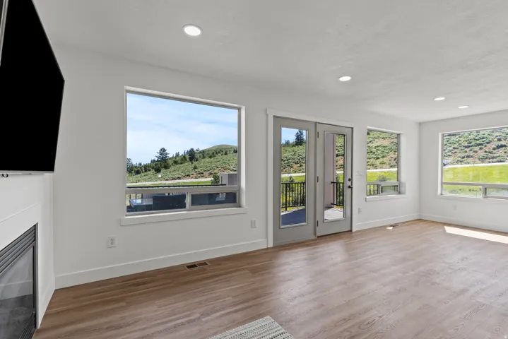 Unfurnished living room with light wood-type flooring, plenty of natural light, a glass covered fireplace, and recessed lighting