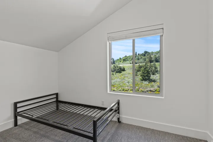 Unfurnished bedroom with lofted ceiling and carpet