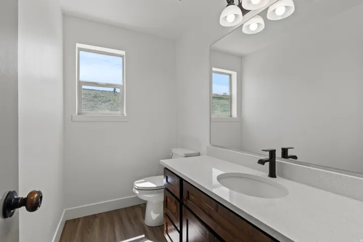 Half bath featuring vanity, dark wood-style floors, and healthy amount of natural light