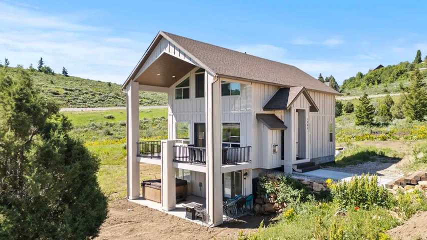 View of side of property with board and batten siding, a shingled roof, and a patio